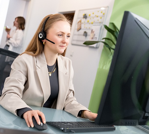 Mitarbeiterin, die mit einem Headset am PC sitzt und telefoniert um die zugesendeten Werbemittel zu besprechen